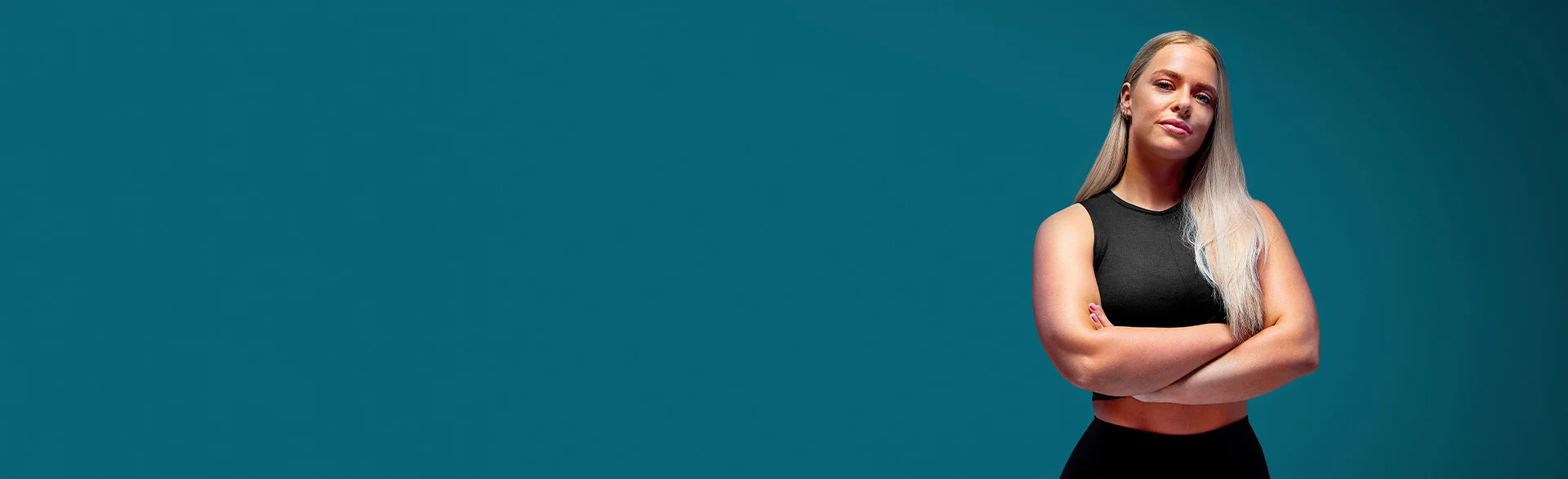 A woman in black coloured activewear with with her arms crossed.